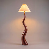 Lámpara decorativa de pie con fuste de madera curvada y diseño atemporal para contract y hogar.