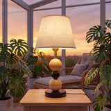 Lámpara decorativa MAYA WOOD AND BLACK encendida al atardecer junto a plantas