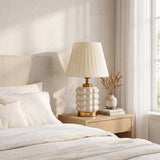 Lámpara decorativa PERLA CREAM AND GOLD junto a cama blanca en dormitorio claro