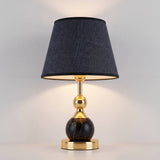 Lámpara decorativa VENUS BLACK AND GOLD encendida junto a ventana con vista nocturna