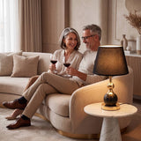 Lámpara decorativa VENUS BLACK AND GOLD encendida en sala elegante con pareja