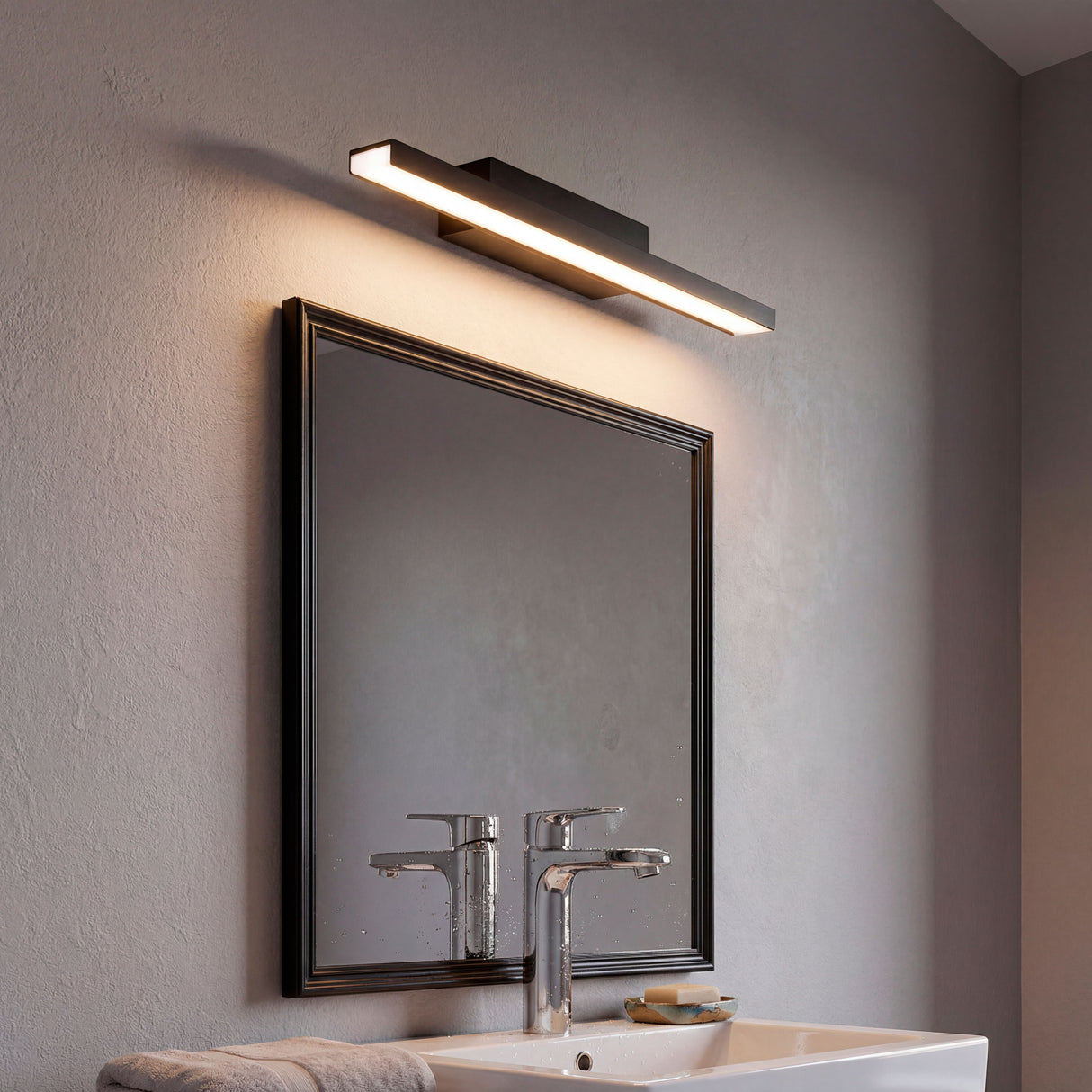 Lámpara de pared Joselyn Black de 12W sobre espejo con marco negro en baño moderno.