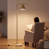 Mujer leyendo en sillón orejero iluminada por lámpara de pie de diseño minimalista.