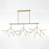 Vista frontal de lampara lineal dorada con ramas y difusores circulares blancos.