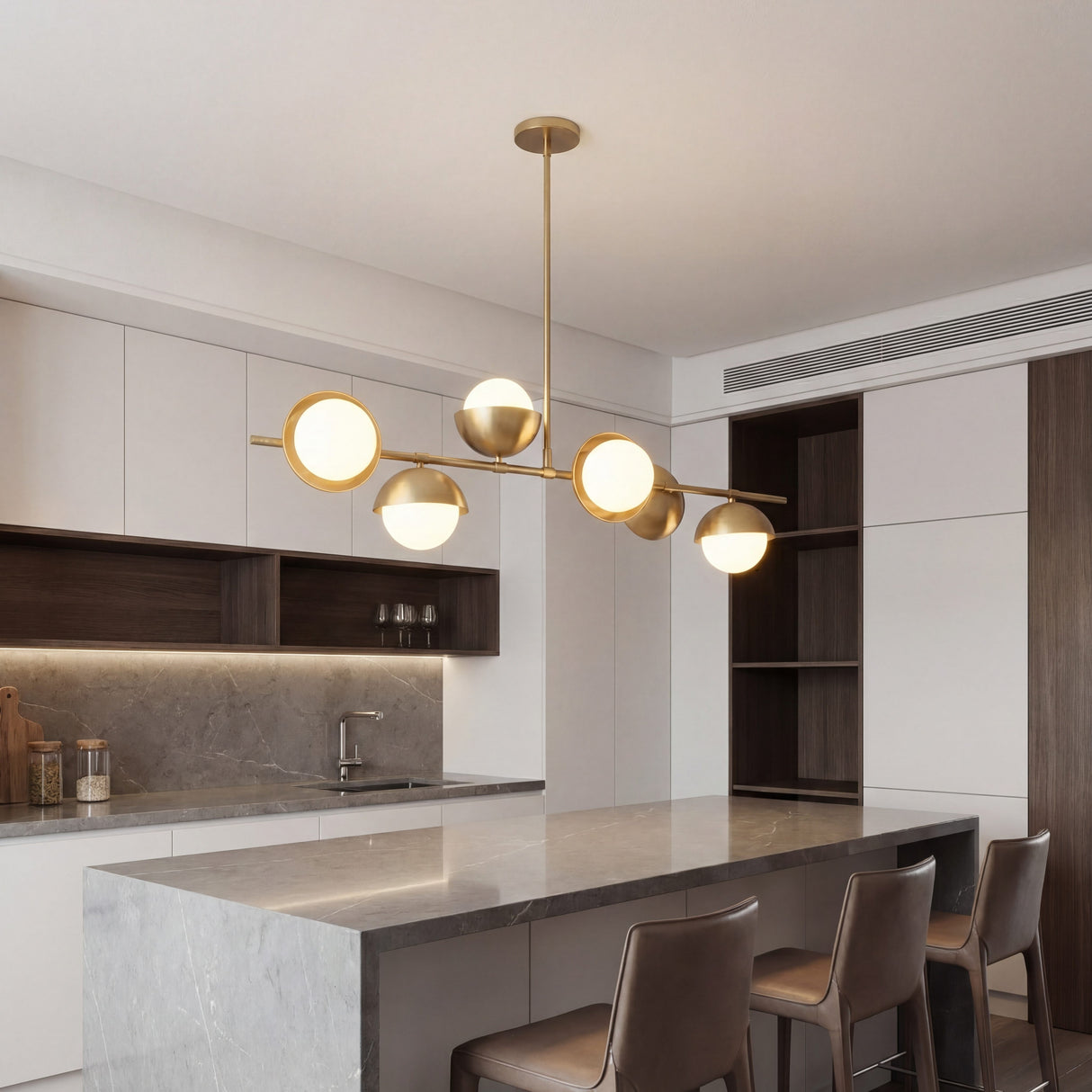 Lampara lineal Nova Gold instalada sobre una isla de cocina moderna con encimeras de marmol.