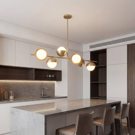 Lampara lineal Nova Gold instalada sobre una isla de cocina moderna con encimeras de marmol.