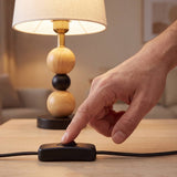 Mano accionando el interruptor de cable de la lámpara de mesa MAYA