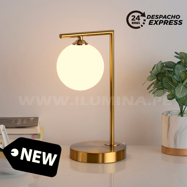 Lámpara de sobremesa dorada con difusor esférico opalino para iluminación técnica decorativa.