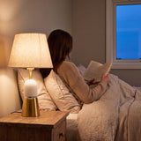 Persona leyendo de noche con la luz cálida de la lámpara de velador Olivia Gold