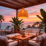 Salón exterior bajo pérgola iluminado por la lámpara Jasmina frente al mar.