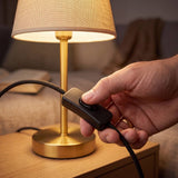 Mano accionando el interruptor de cable de la lámpara de mesa NORA GOLD