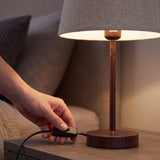Mano accionando el interruptor de cable de la lámpara de mesa NORA WALNUT