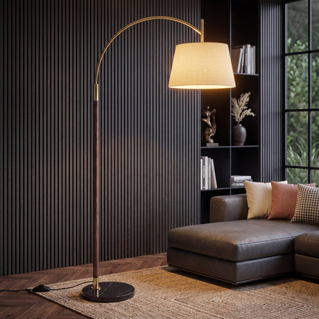 Lámpara de pie de arco dorada y madera de nogal en sala minimalista moderna junto a un sofá de cuero.