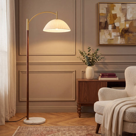 Lámpara de arco con pantalla plisada blanca, cuerpo de madera y base de mármol en salón de diseño clásico contemporáneo.