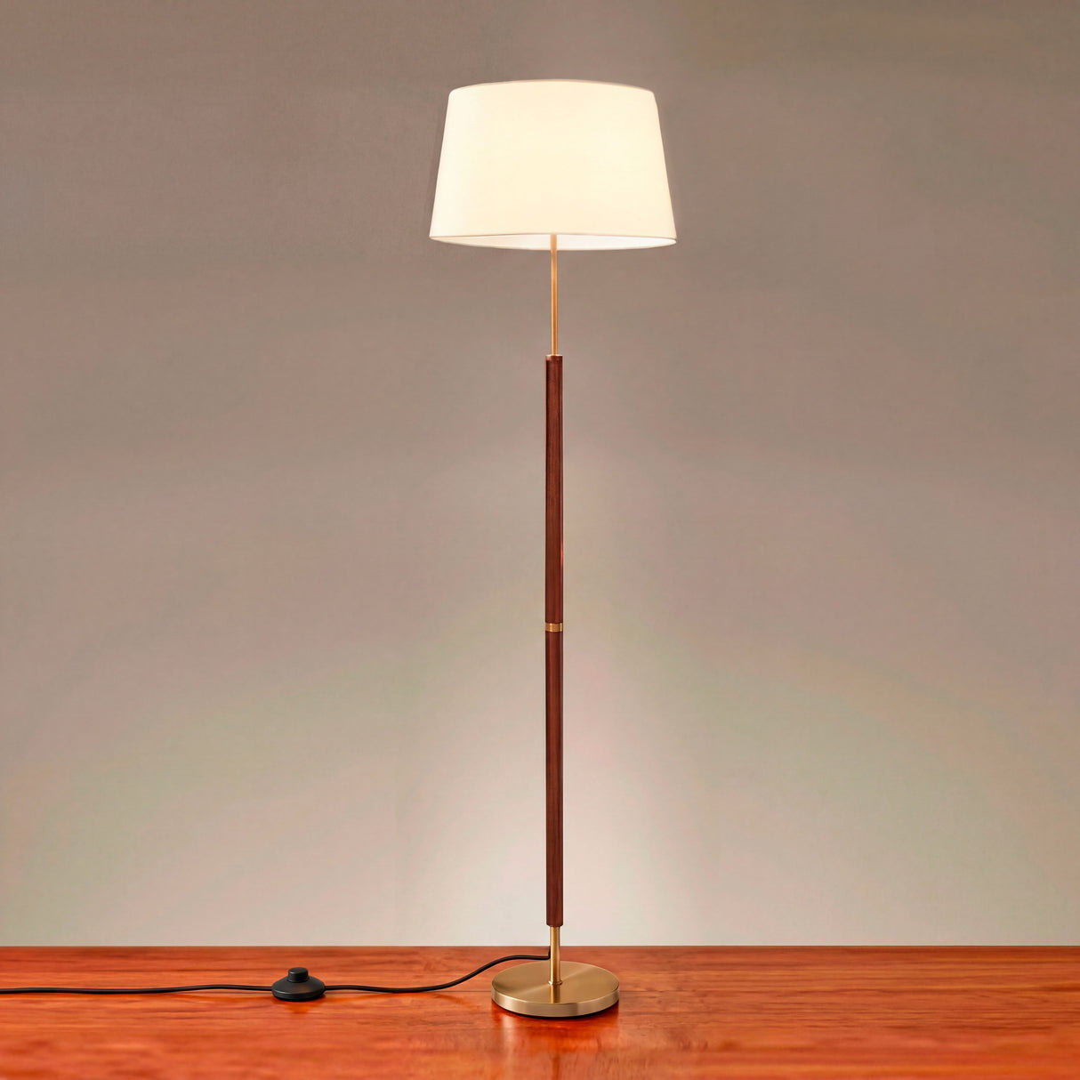 Vista completa de la lámpara Jessica Cedro encendida sobre suelo de madera.