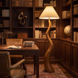 Estudio elegante iluminado con lámpara exenta de madera veteada que aporta sobriedad y calidez al espacio de trabajo.