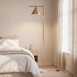 Lámpara de pie dorada junto a la cama en dormitorio de arquitectura moderna.