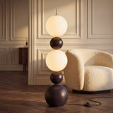 Luminaria escultural de esferas apiladas en salón clásico contemporáneo junto a sillón bouclé blanco.