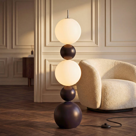 Luminaria escultural de esferas apiladas en salón clásico contemporáneo junto a sillón bouclé blanco.