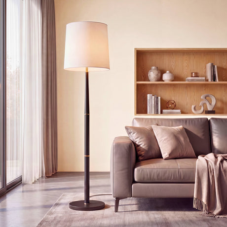 Lámpara de suelo contemporánea con fuste negro estilizado y pantalla cilíndrica blanca en salón residencial.