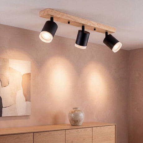 Lámpara de techo BRISA con base de madera y 3 spots negros iluminando un muro nude