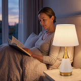 Lámpara de velador AMIRA WHITE AND GOLD iluminando la lectura nocturna en la cama