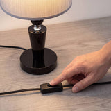 Mano encendiendo la lámpara con el interruptor en línea del cable