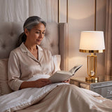 Mujer leyendo en la cama junto a la luz cálida de la lámpara de velador