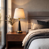 Lámpara de velador beige y negra sobre mesa de noche en dormitorio moderno