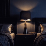 Lámpara de velador CLEO GOLD encendida de noche con luz ambiental cálida