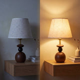 Lámpara de velador FREYA WALNUT AND BLACK con luz cálida en ambiente oscuro
