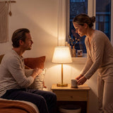 Lámpara de velador MARGOT WOOD AND GOLD encendida en dormitorio con pareja