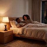 Lámpara de velador con luz cálida junto a pareja descansando de noche