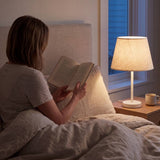 Lámpara de velador NORA WHITE iluminando la lectura nocturna en el dormitorio