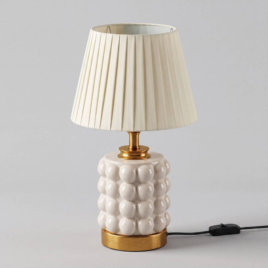 Lámpara de velador PERLA CREAM AND GOLD con luz cálida sobre mesa de noche