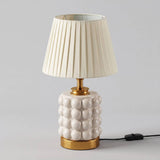 Lámpara de velador PERLA CREAM AND GOLD con luz cálida sobre mesa de noche