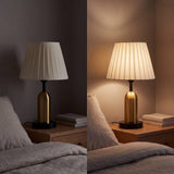Lámpara de velador de latón antiguo sobre mesa de noche junto a la cama