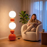 Mujer leyendo en sillón junto a luminaria de pie vertical con iluminación técnica difusa y confortable.