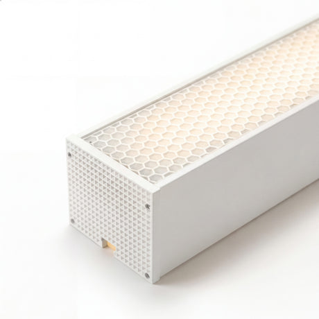 Primer plano de difusor microprismático en luminaria blanca con acabado premium y luz cálida.