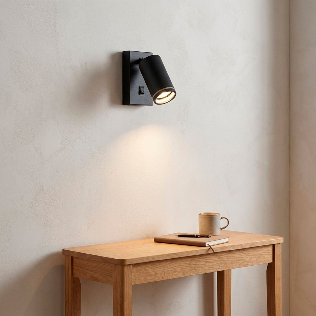 Iluminación ambiental cálida sobre mesa auxiliar en rincón de lectura con luminaria negra.