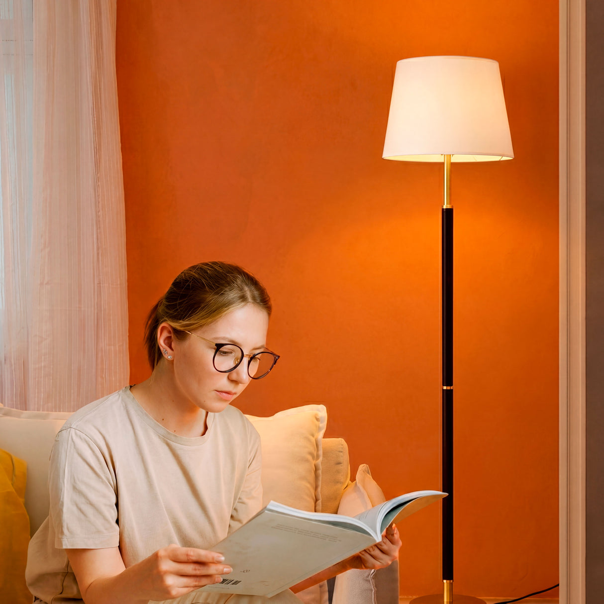 Mujer leyendo un libro en el sofá bajo la iluminación ambiental suave de la lámpara.