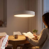 Mujer leyendo bajo luz LED circular de alta eficiencia y confort visual en despacho.