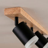 Detalle en primer plano de la base de madera natural y proyectores en aluminio mate con acabado premium.
