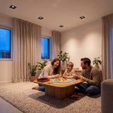 Familia jugando en sala iluminada por ojos de buey cuadrados negros empotrados