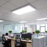 Panel LED rectangular de 36W en techo técnico de oficina con estaciones de trabajo.