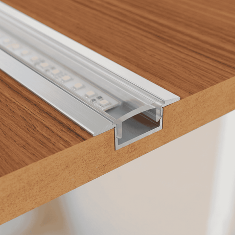 Detalle de instalación de perfil de aluminio en ranura de madera para mobiliario a medida.