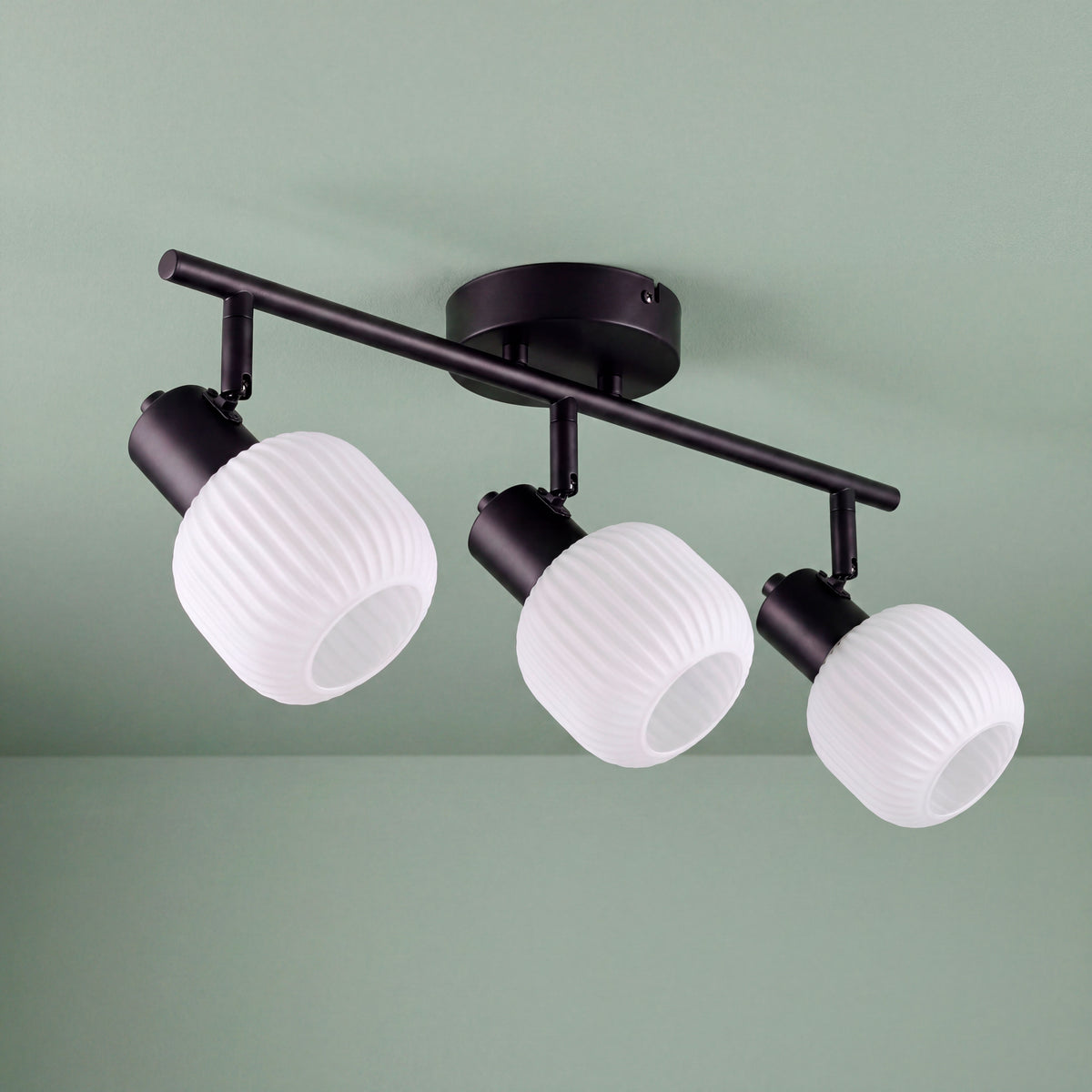 Plafón de sobreponer con tres pantallas de cristal estriado en blanco y estructura en aluminio negro.