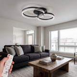 Lámpara de techo LED negra de doble círculo en un salón moderno con tonos grises.