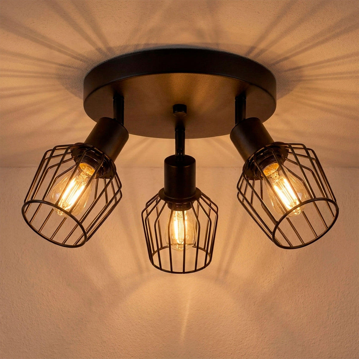 Plafón circular de tres luces tipo jaula en aluminio negro con proyección radial cálida sobre cielo raso.