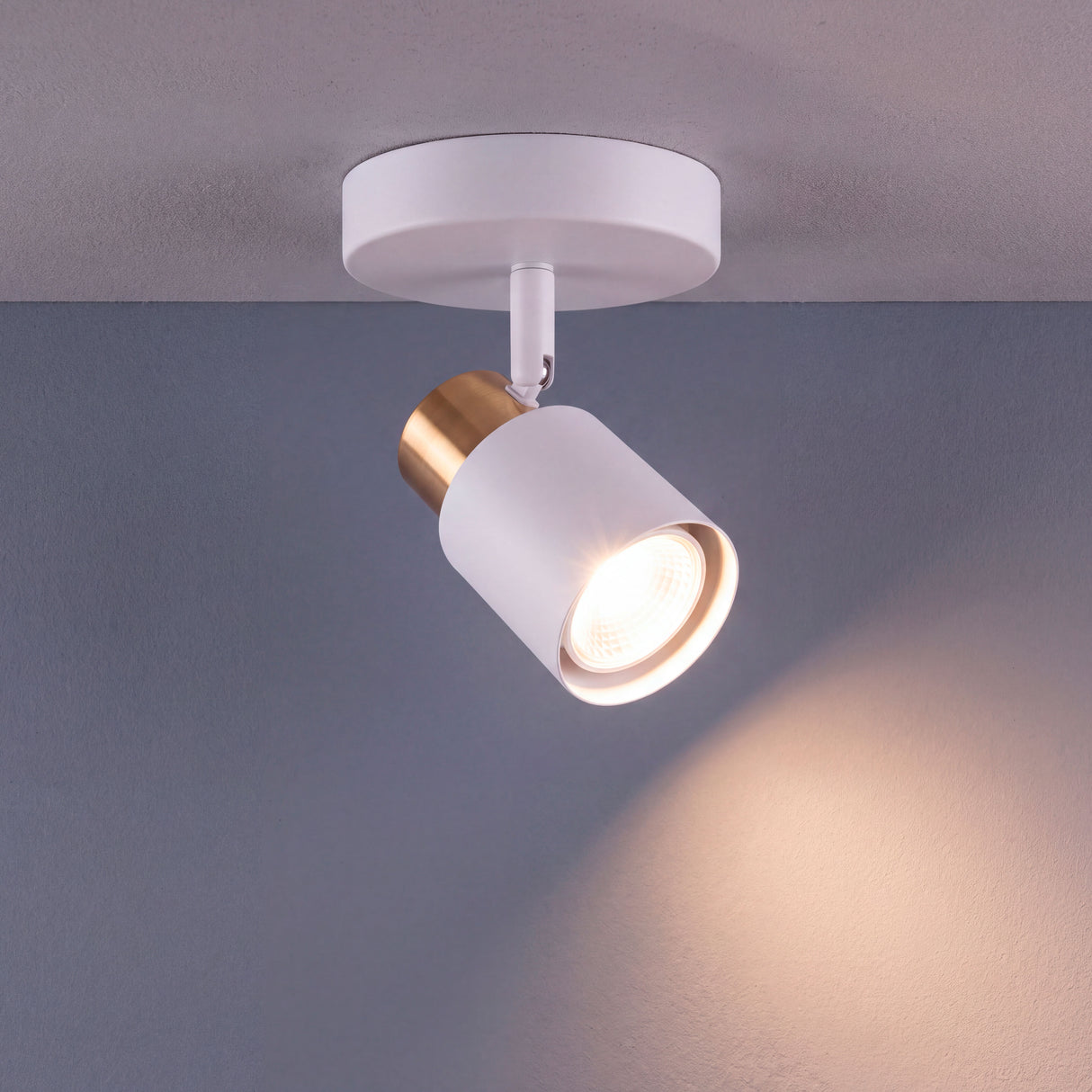 Haz de luz directa proyectado desde foco de sobreponer con rotación orientable sobre superficie plana.